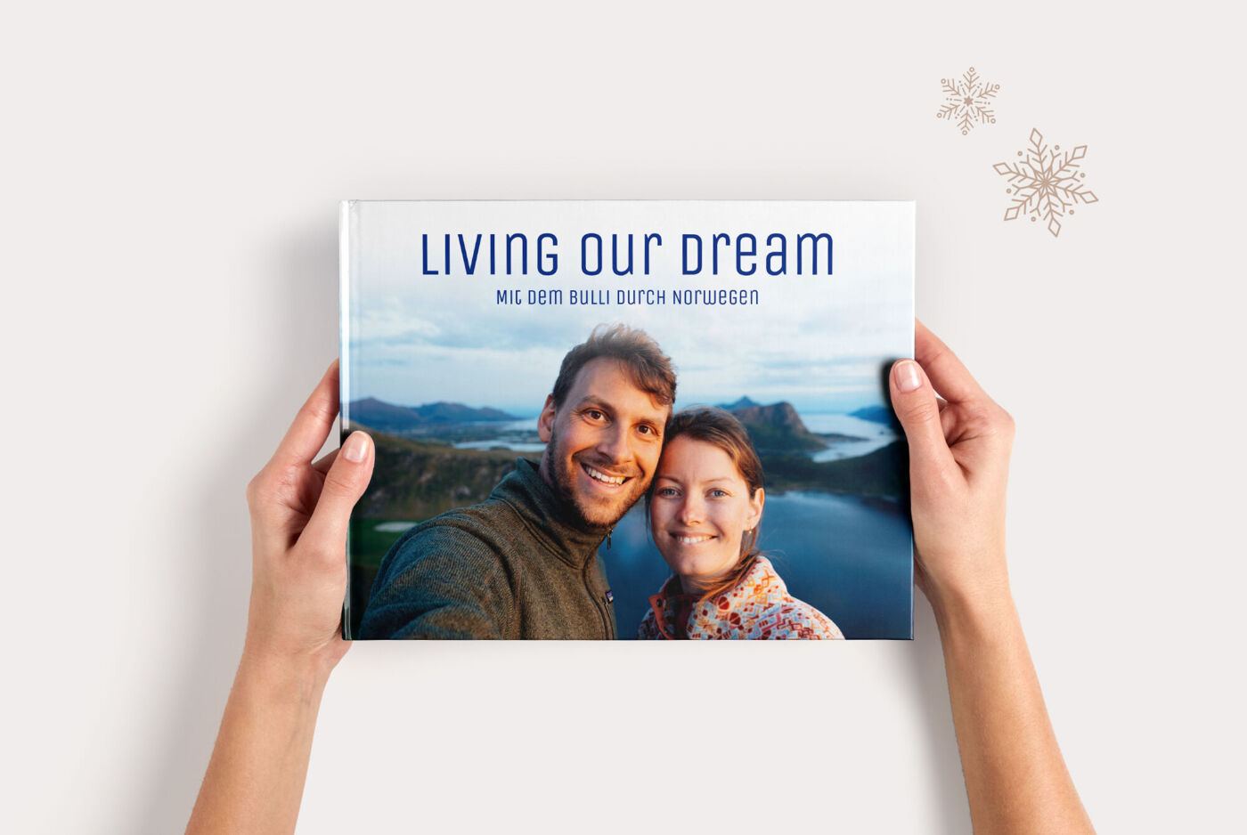 Ein Paar hält ein CEWE FOTOBUCH Groß Panorama mit dem Titel „Living Our Dream“ in den Händen.