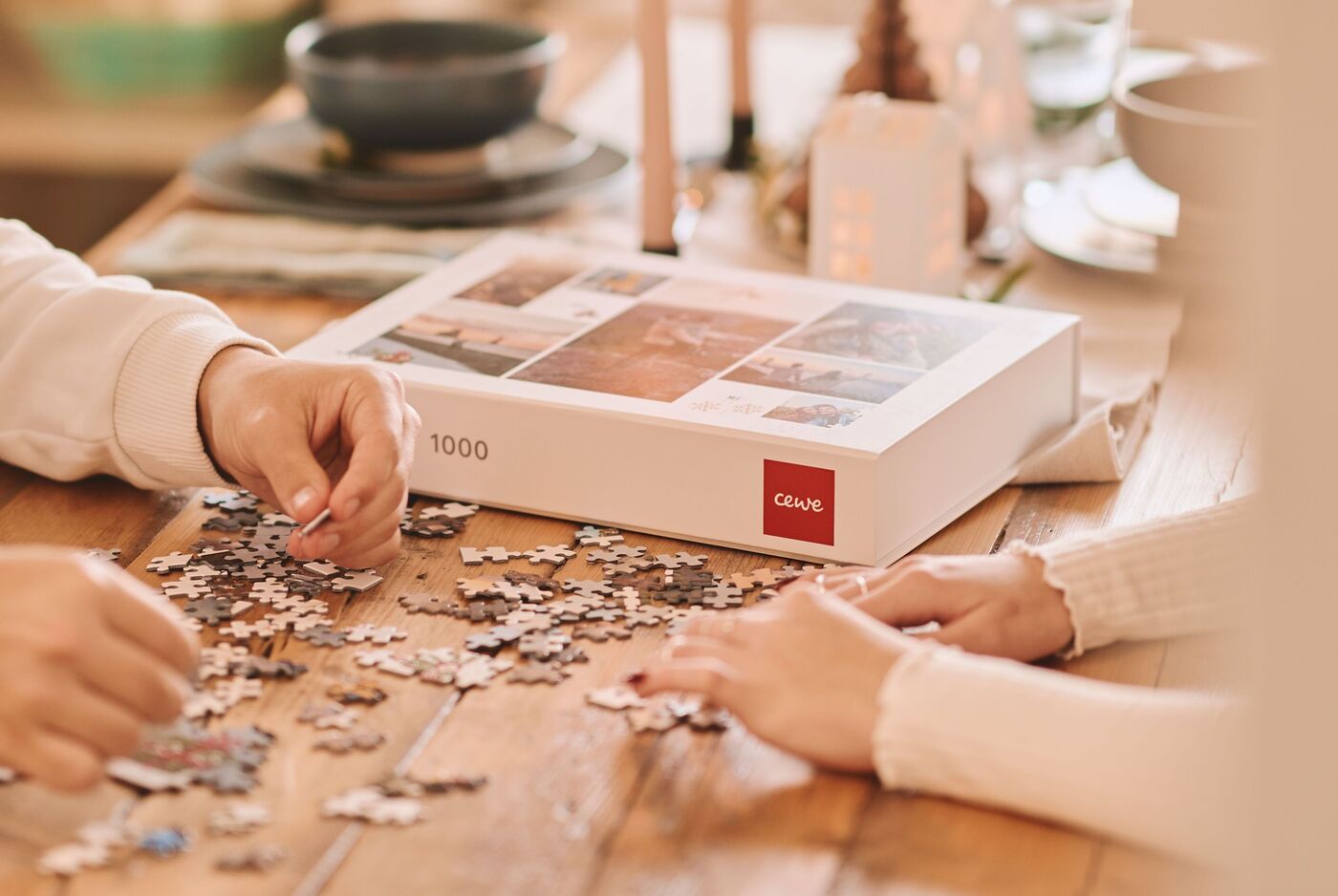 Zwei Personen sitzen an einem Holztisch und setzen gemeinsam ein Puzzle zusammen