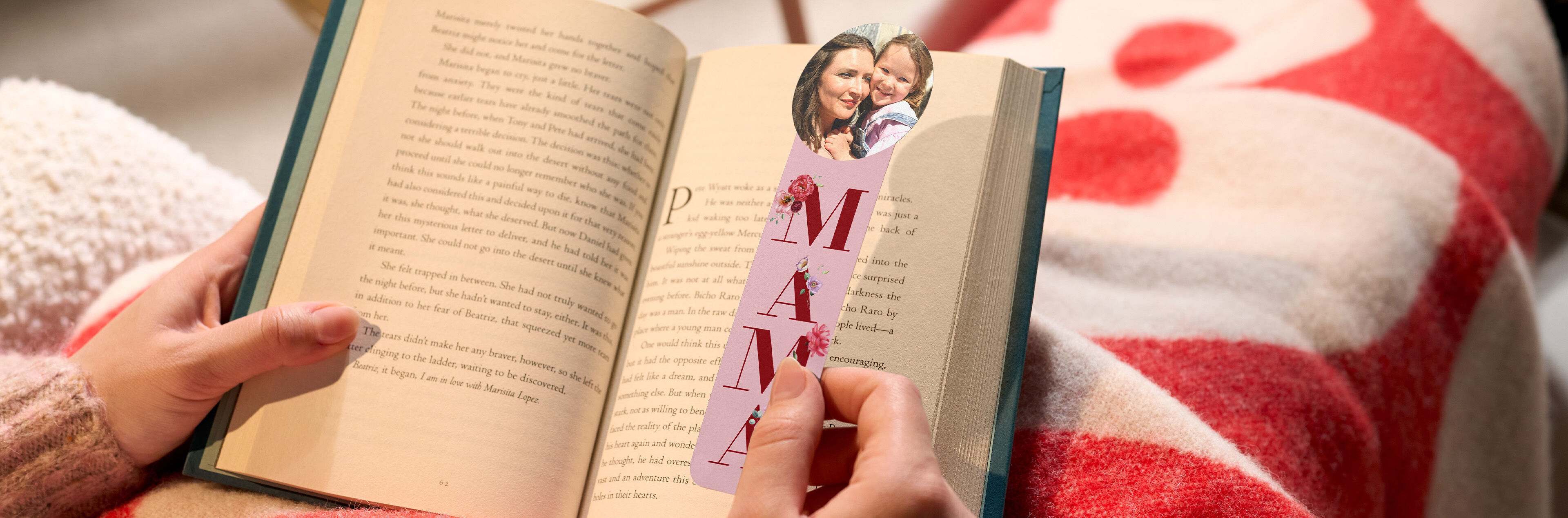 Eine Person liest ein Buch mit einem persönlichen Lesezeichen für Mama.