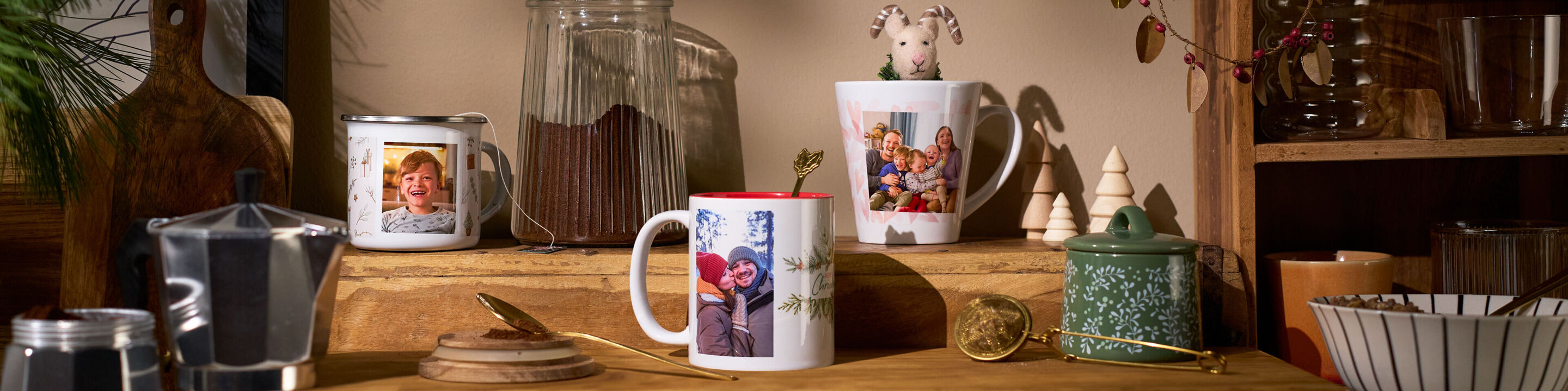 Drei personalisierte Fototassen mit Familienfotos in einer gemütlichen und weihnachtlichen Küche.