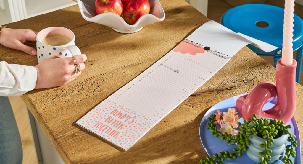 Auf einem Tisch liegt ein Fotokalender, das Design ist orange gehalten und zeigt den Schriftzug „Always better together“.