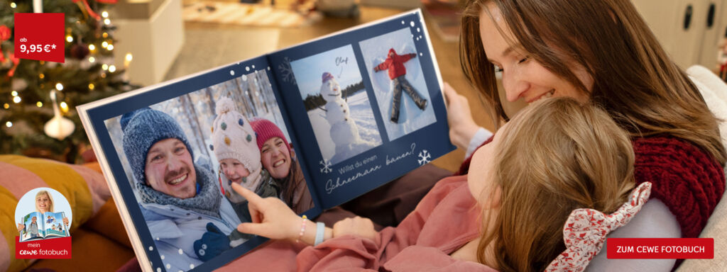 Eine Familie betrachtet gemeinsam ein CEWE FOTOBUCH mit Wintererinnerungen