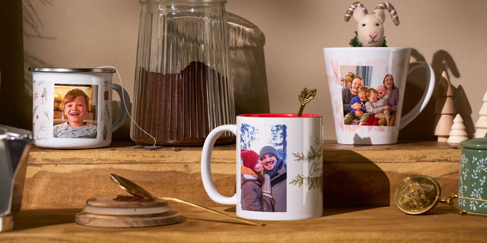 Drei personalisierte Fototassen mit Familienfotos in einem Küchenregal in gemütlicher und weihnachtlicher Atmosphäre.
