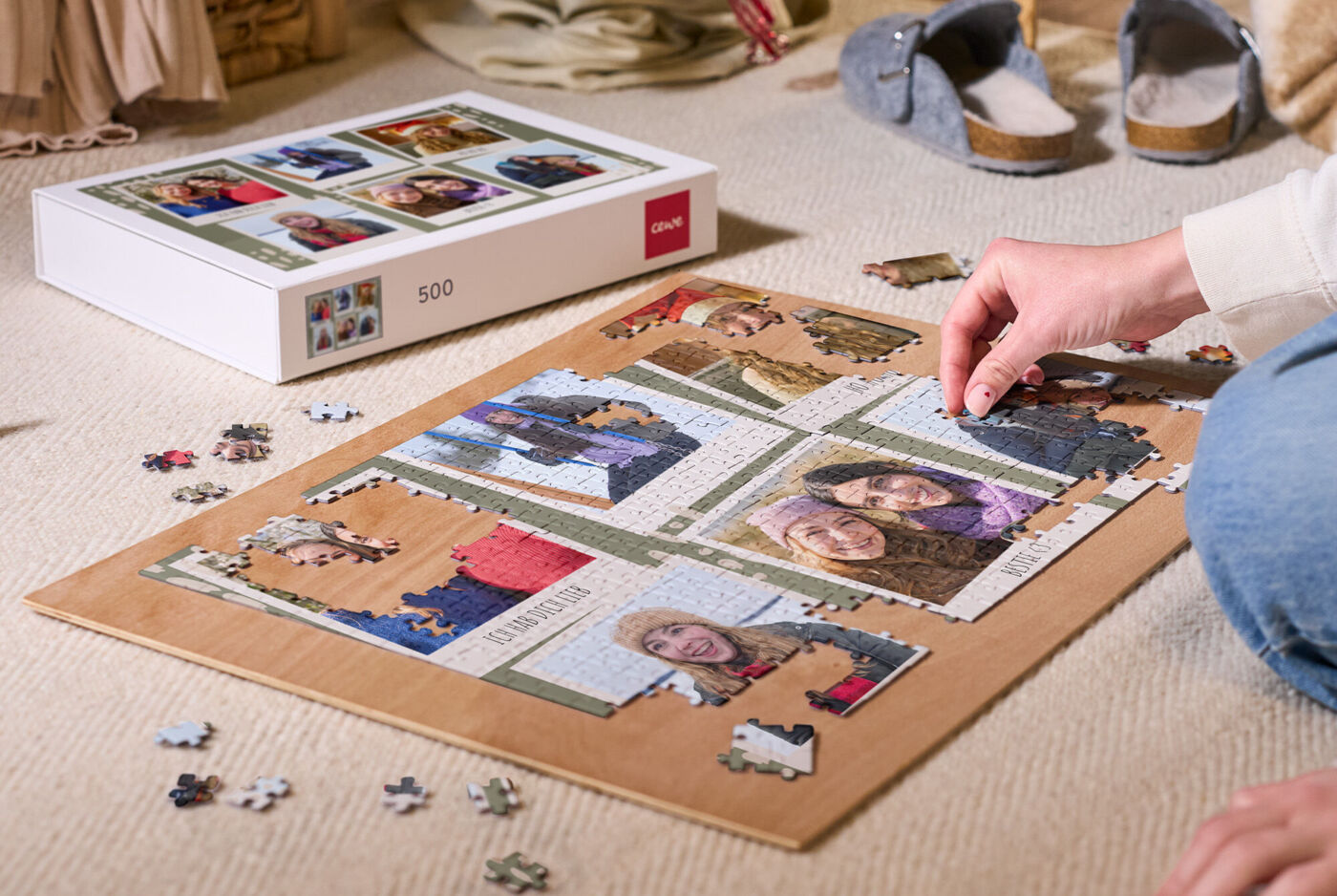 Person legt ein Fotopuzzle mit Familienfotos auf dem Boden zusammen, daneben liegt die Puzzlepackung