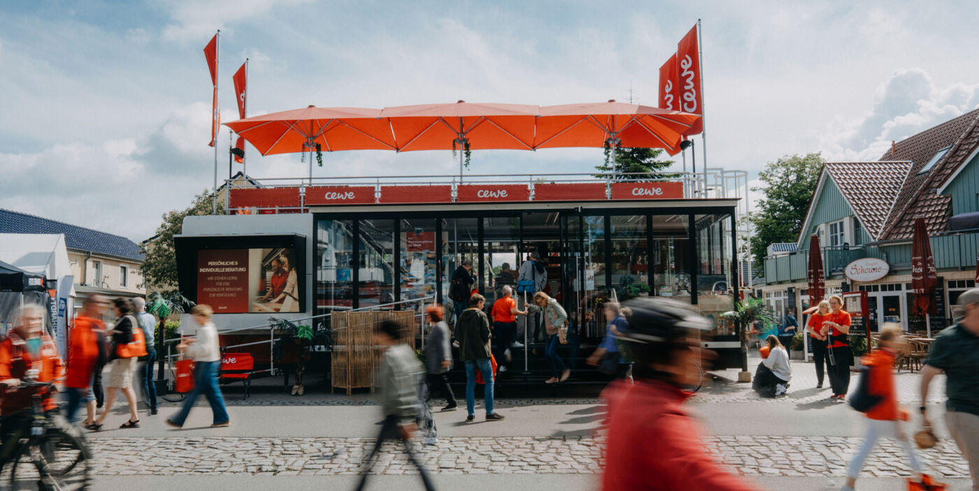 Der CEWE Truck steht in einer Einkaufsstraße. Drumherum sind viele Menschen unterwegs.
