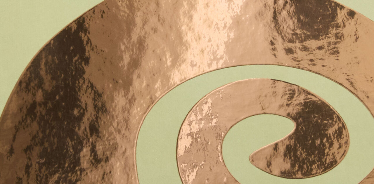 Zarte Spiralmuster in Roségold-Veredelung auf grünem Hintergrund.