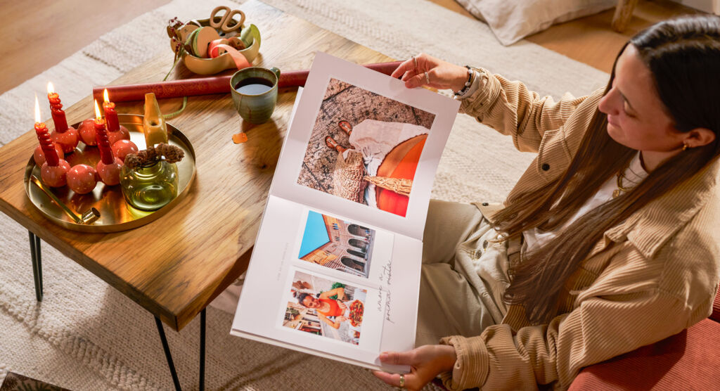 Eine Frau hält ein CEWE FOTOBUCH in den Händen, in dem farblich aufeinander abgestimmt Fotomotive abgebildet sind.