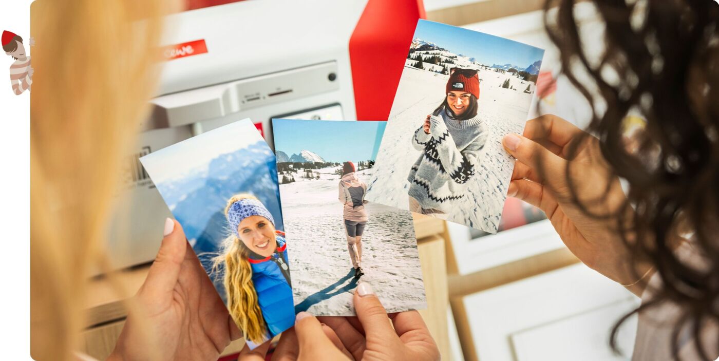 Zwei Personen an der Fotostation halten schöne Urlaubsfotos in den Händen.