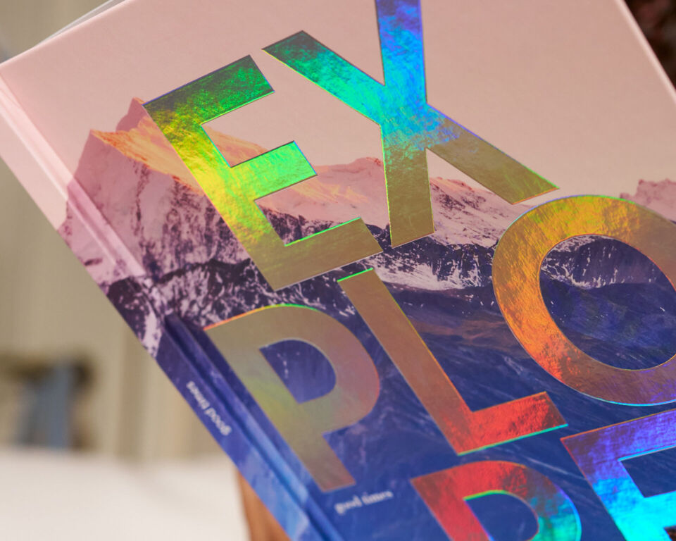Eine Person hält ein CEWE FOTOBUCH mit einer holografischen Veredelung auf dem Cover.