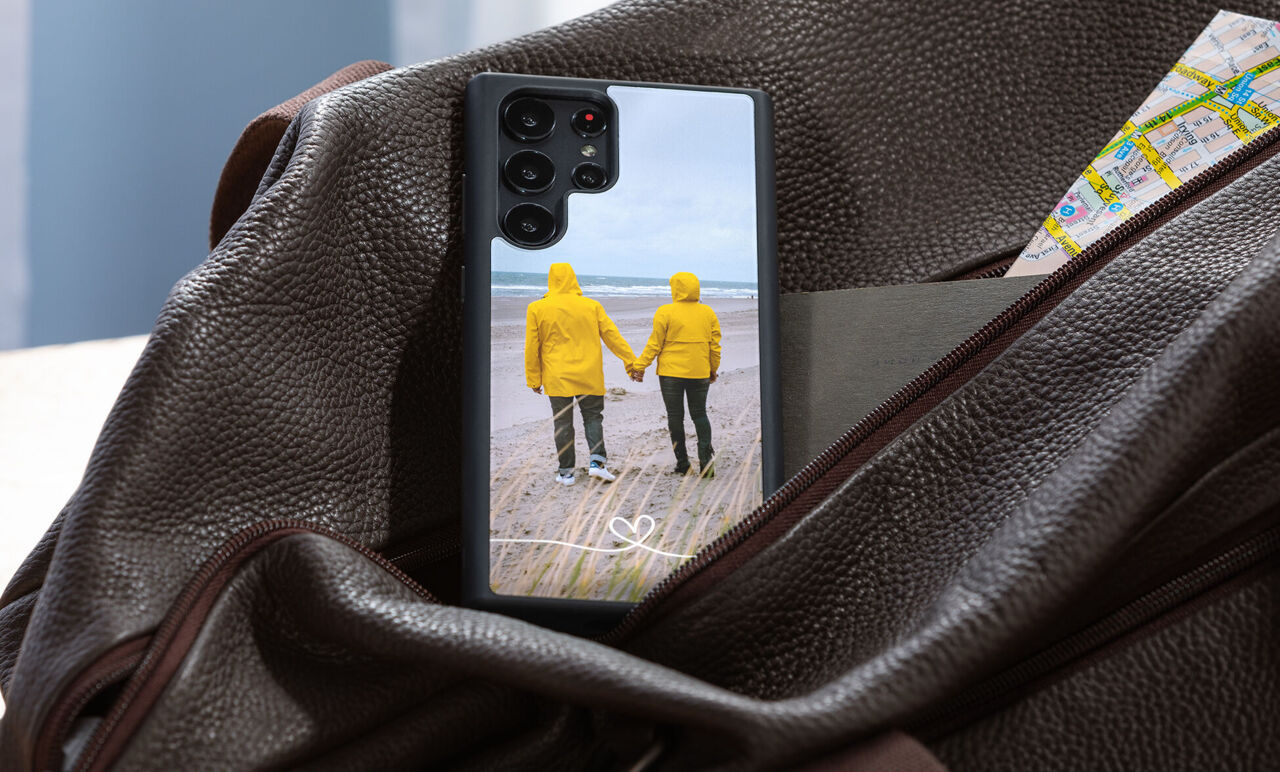 Ein Smartphone mit einem Foto von einer Person am Strand, umgeben von Luftballons