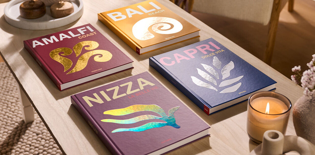 Verschiedene CEWE Fotobücher mit bunten Designs auf einem Tisch.