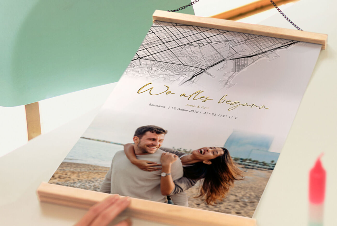 Person hält ein CEWE Poster mit Posterleiste und Goldveredelung, auf dem ein Strandfoto von zwei lachenden Personen zu sehen ist.