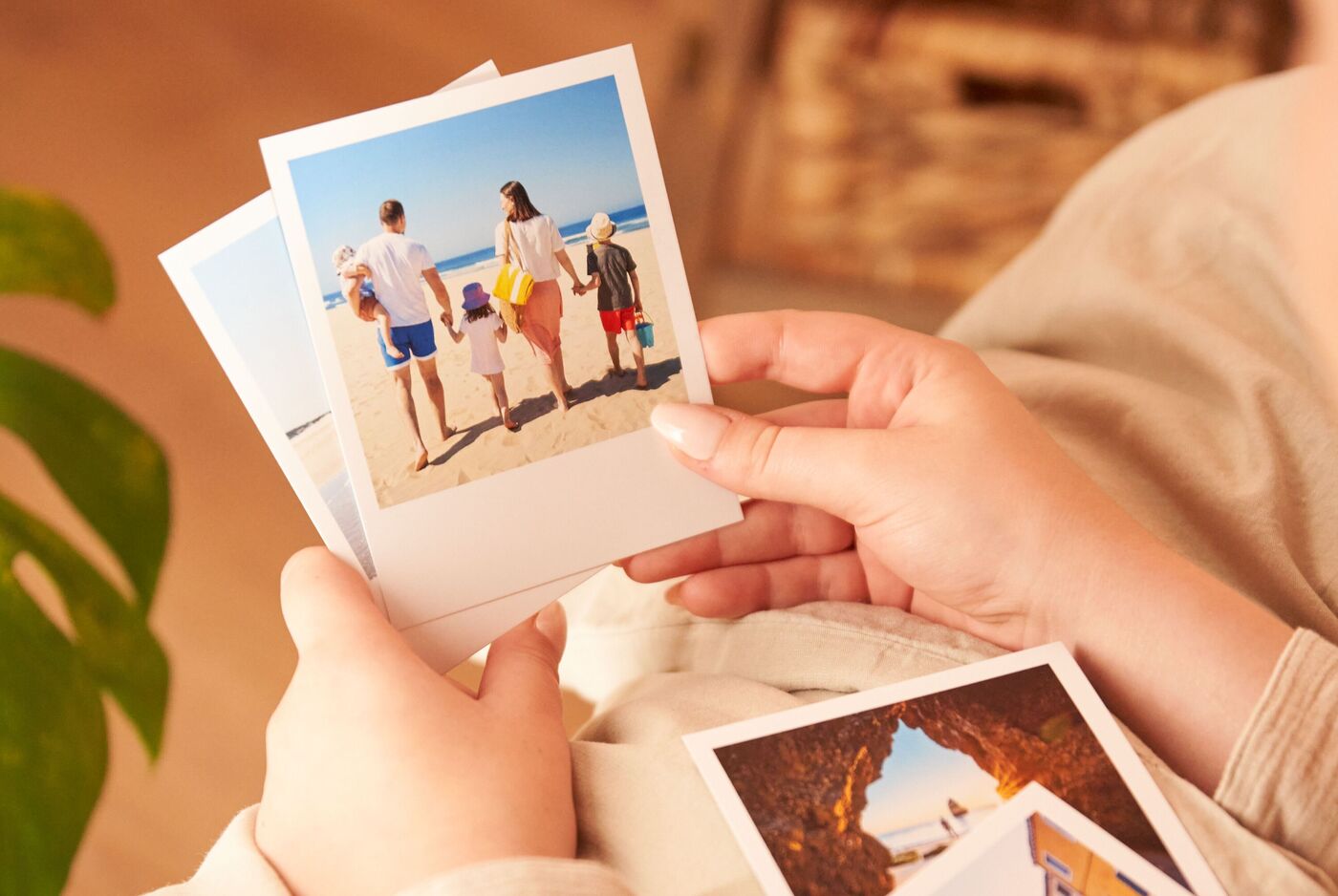 Eine Person hält mehrere quadratische Fotoabzüge im Retro-Stil mit weißem Rahmen in der Hand