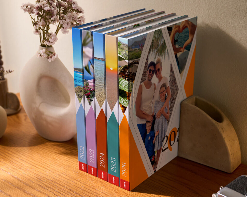 Fünf stilvolle CEWE FOTOBÜCHER stehen nebeneinander auf einem Tisch.