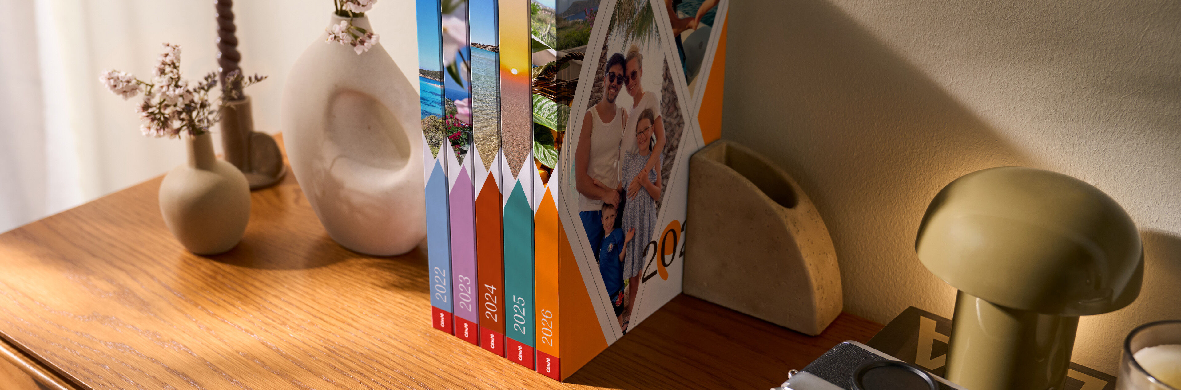 Verschiedene CEWE Fotobücher in einer Reihe auf einem Holztisch.