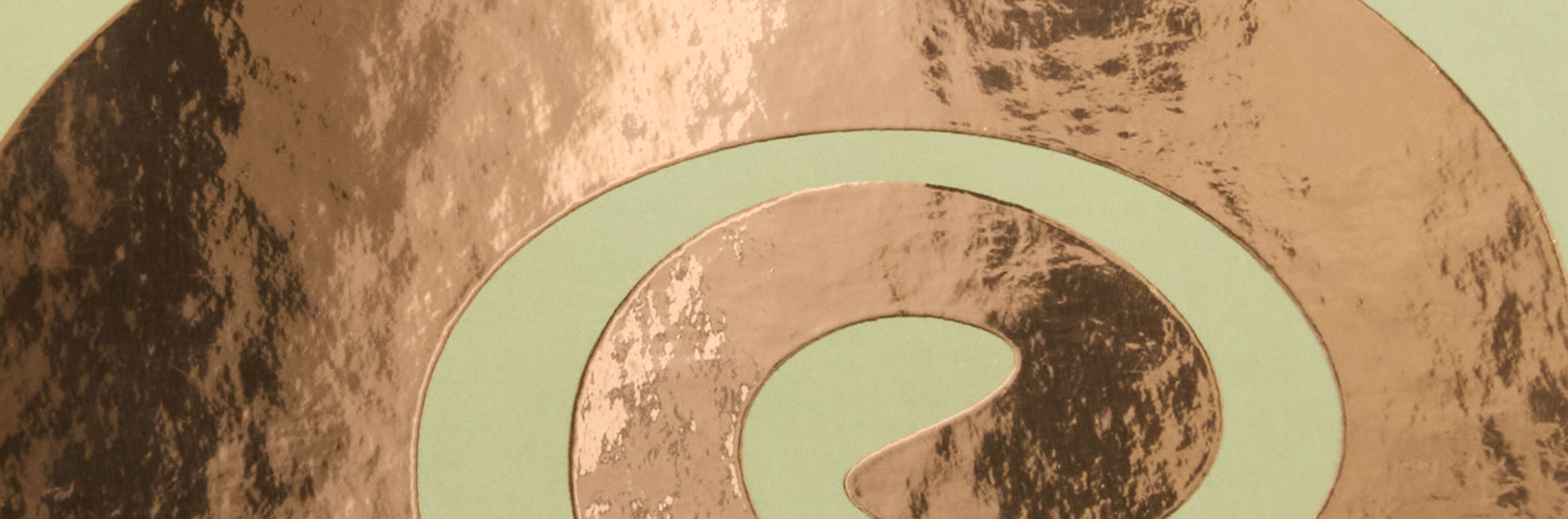 Zarte Spiralmuster in Roségold-Veredelung auf grünem Hintergrund.