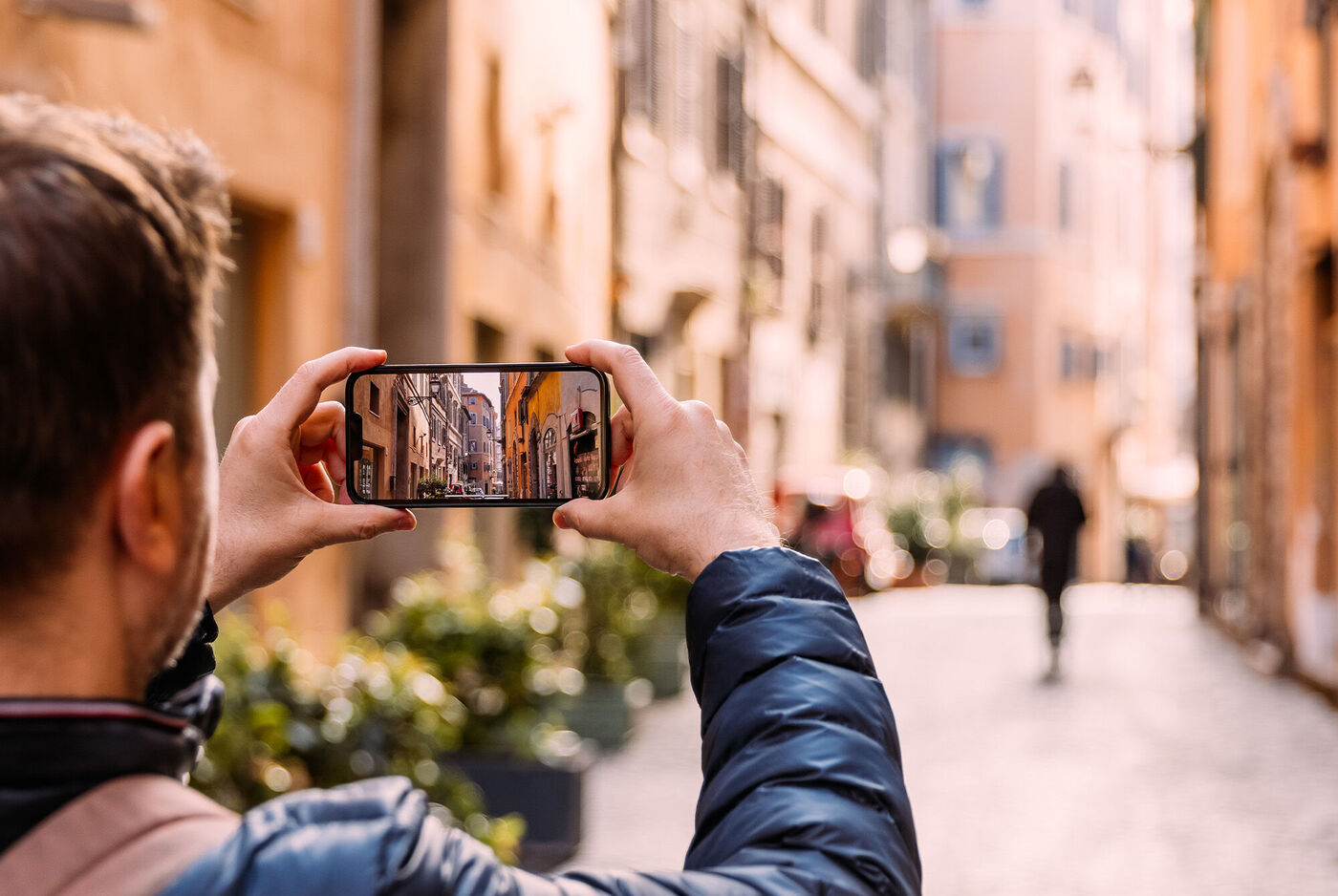 Ein Mann fotografiert eine malerische Gasse mit seinem Smartphone