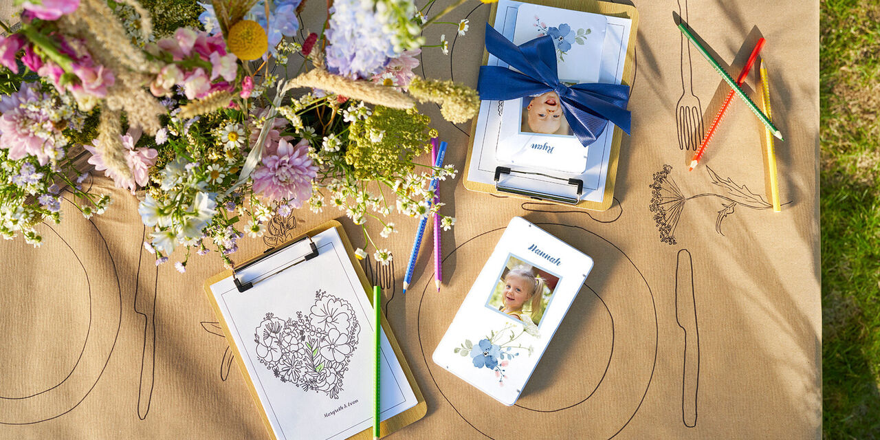 Auf einem Tisch liegen Buntstifte in einer Metallbox im floralen Design mit Kinderfoto und ein Bild zum Ausmalen.