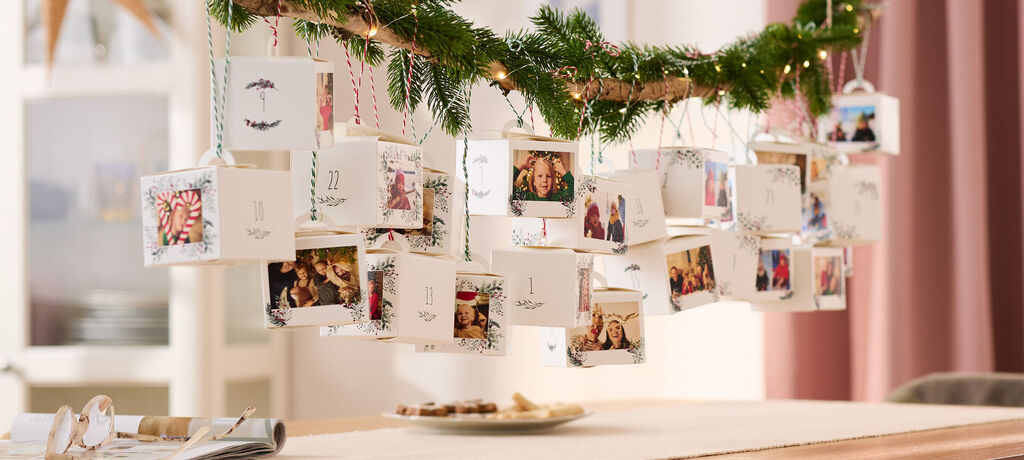 Ein weihnachtlich dekorierter Adventskalender aus 24 einzelnen Schachteln, die mit verschiedenen Fotos bedruckt sind.
