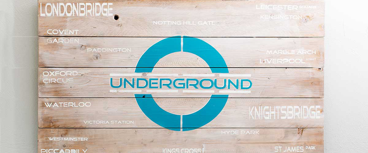 Holzschild mit dem Logo der Londoner U-Bahn-Station London Bridge.
