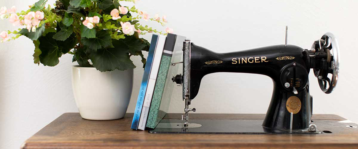 Blumentopf und Fotobücher, kombiniert mit einer Singer-Nähmaschine.