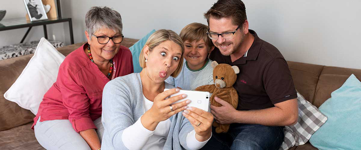 Hannah Fischer bringt ihre Familie und Schwiegermutter Uschi mit einer Grimasse zum Lachen. Dabei fotografieren sie sich mit einem Smartphone.