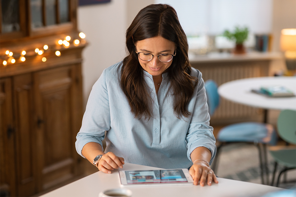 Jana zeigt die CEWE FOTOBUCH Seiten auf ihrem Tablet.
