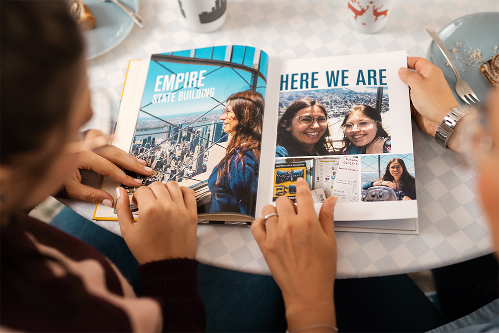 So weit oben:Jana und Lilli blättern durch das CEWE FOTOBUCH. Zu sehen ist auch ein Foto mit dem Empire State Building.