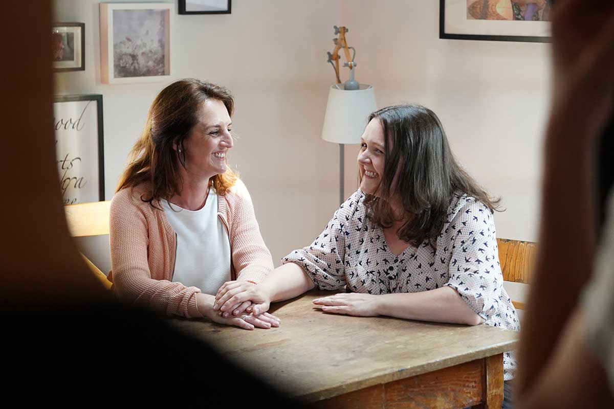 Tina Kneitz und Melanie Kofler sitzen gemeinsam am Tisch und unterhalten sich.