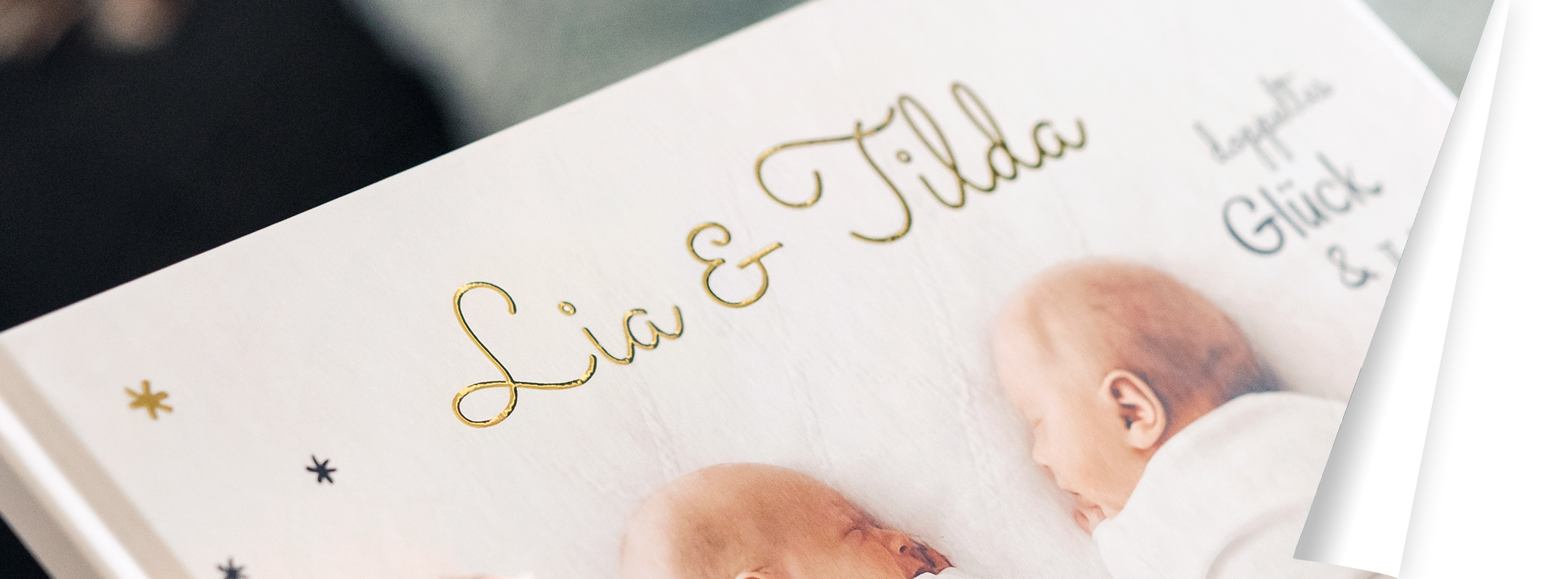Titelbild des Fotobuchs, das Lia und Tilda zeigt. Ihre Namen stehen in einem goldenen Schriftzug.
