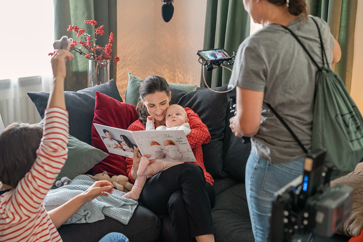 Nadine betrachtet gemeinsam mit dem Baby auf ihrem Arm das Fotobuch.