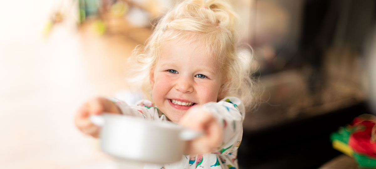 Martha hat in ihrer Spielküche gekocht und bittet lachend zu Tisch.