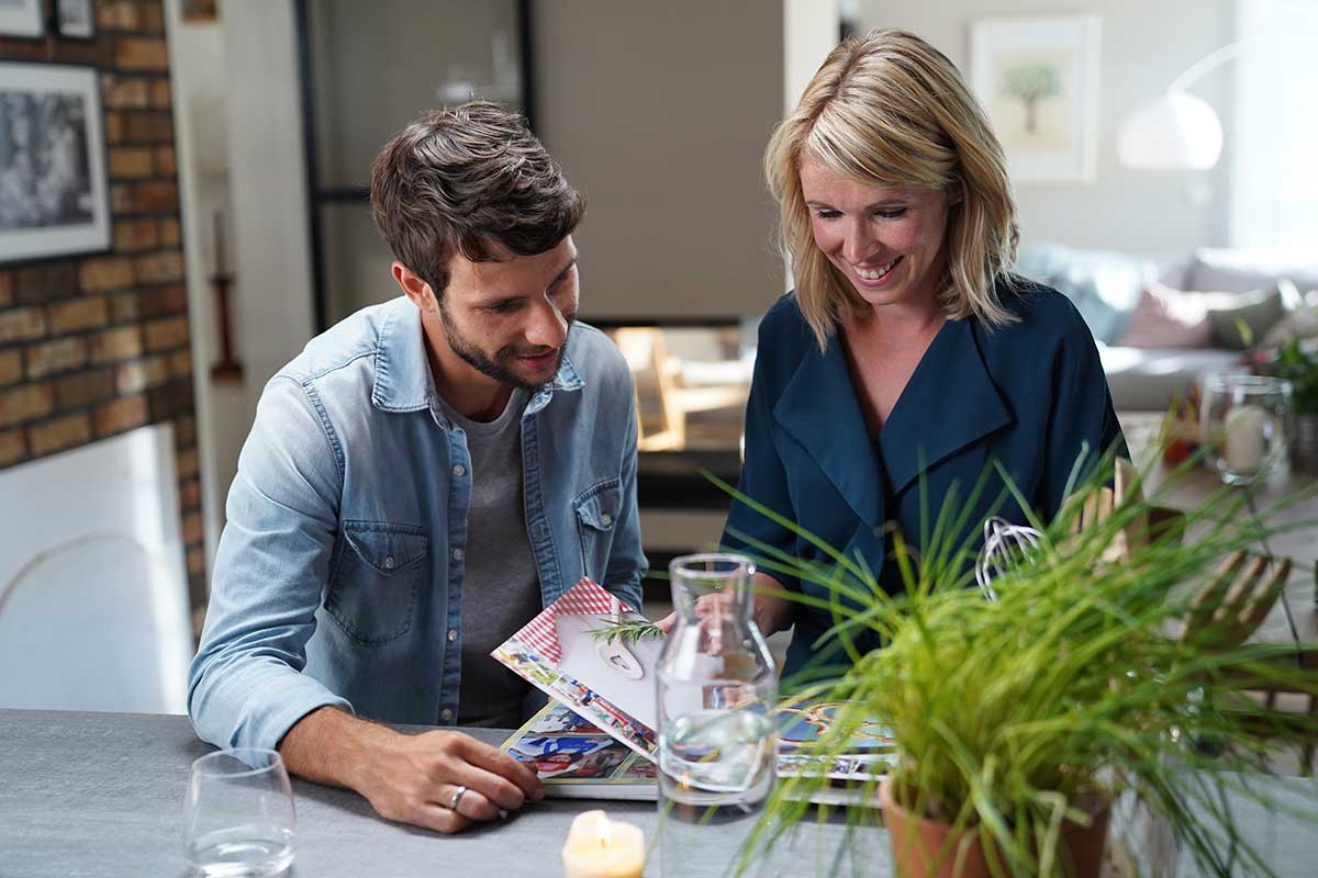 Martin und Marlén Wernicke blättern durch ein CEWE FOTOBUCH ihrer Familie.