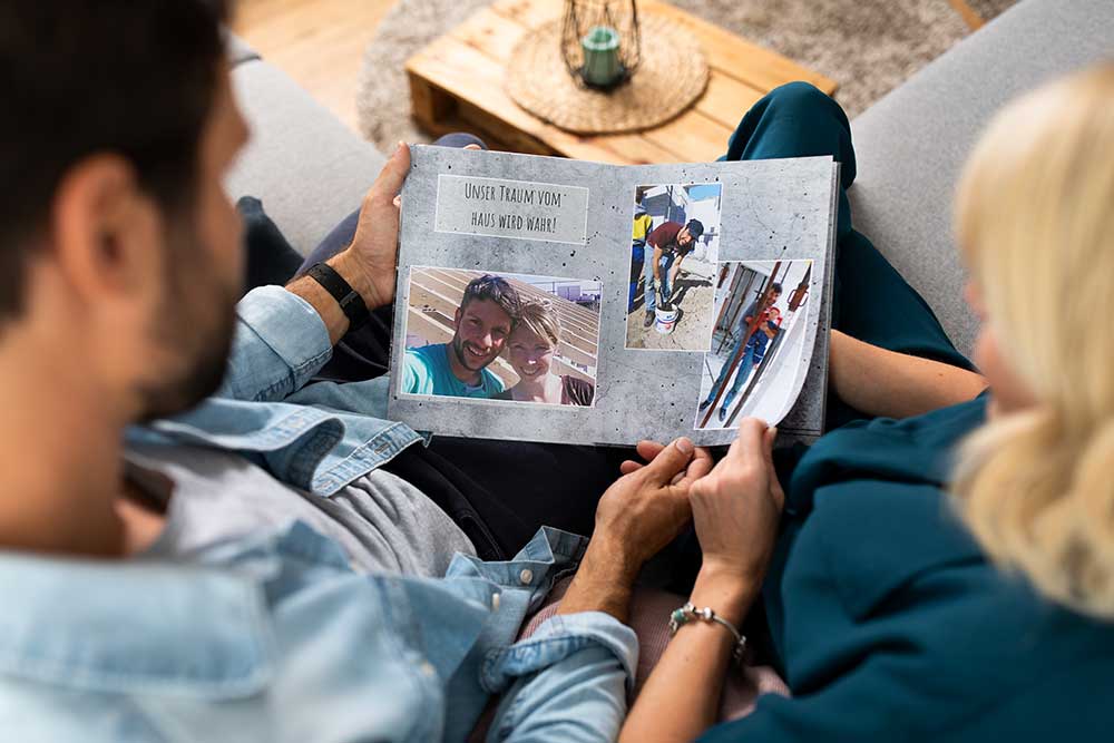 Marlén und Martin Wernicke schauen sich ein CEWE FOTOBUCH an, das ihre gemeinsame Vergangenheit zeigt.